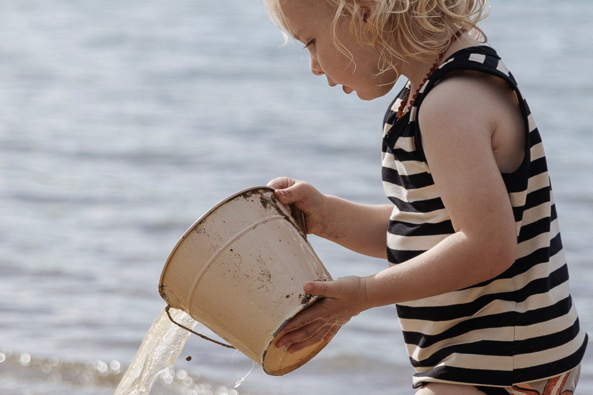 Child wearing Stripe Tank playing with water and bucket