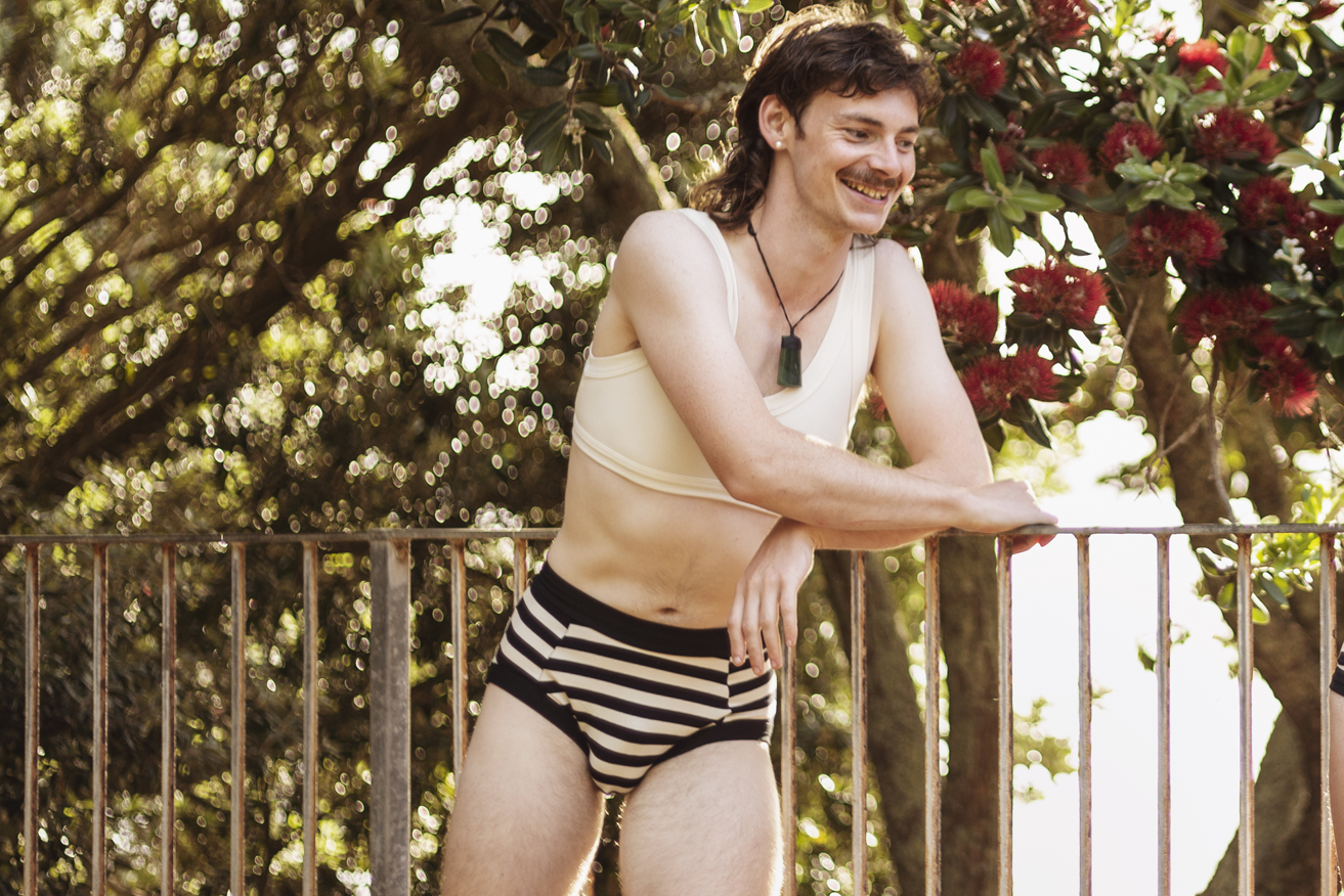 Person leaning on a fence wearing Pouch Briefs and a Crop. 