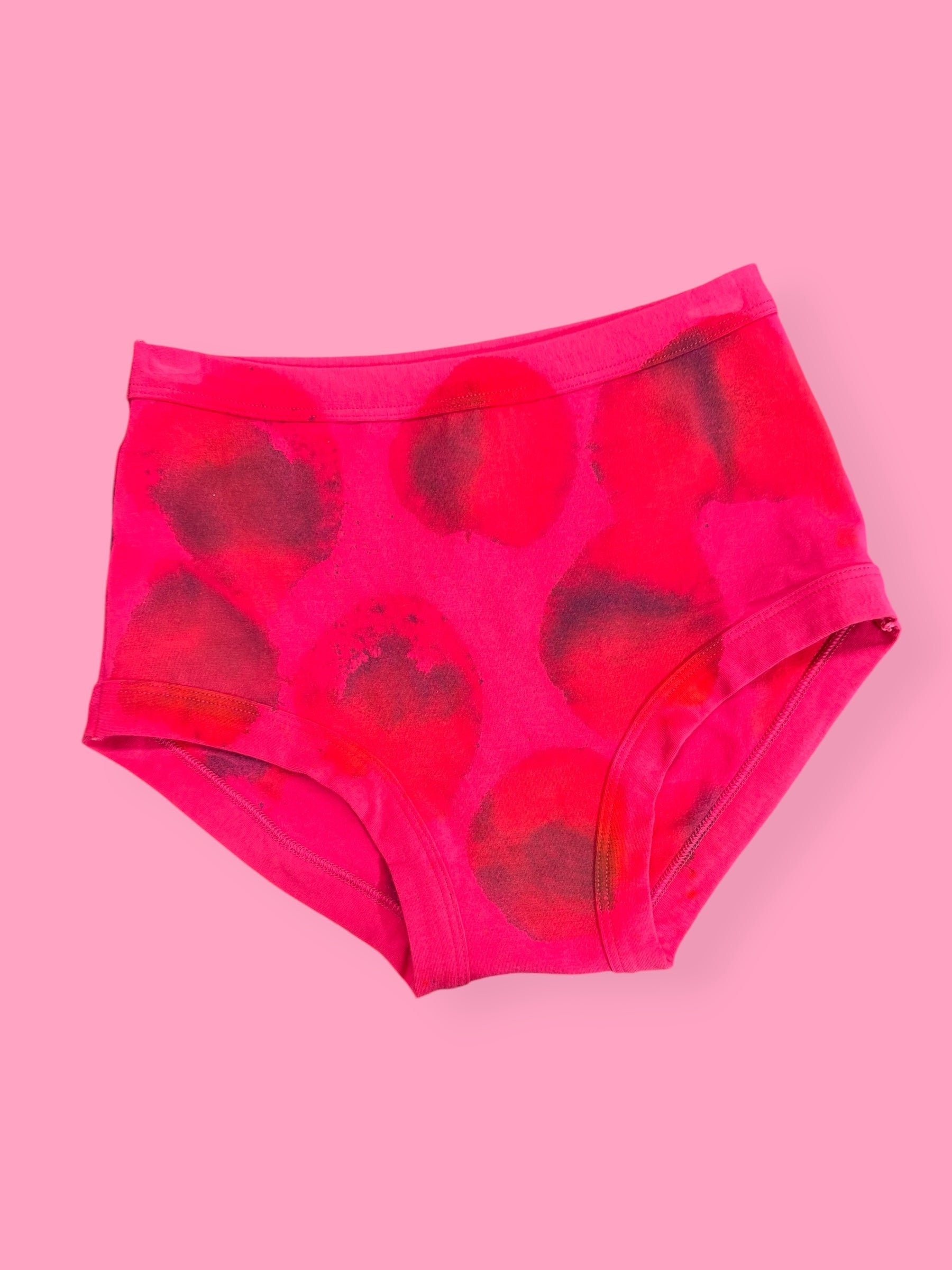 Pink high-waisted underwear with red patterns on a pink background