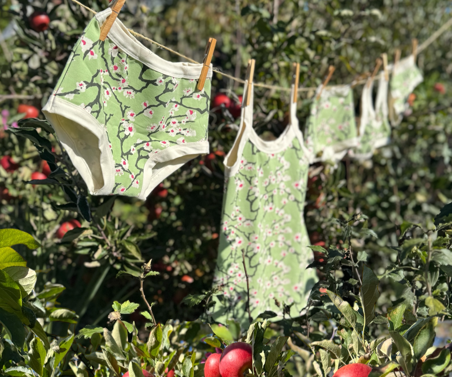Blossom printed garments hanging on a clothesline amongst an apple tree