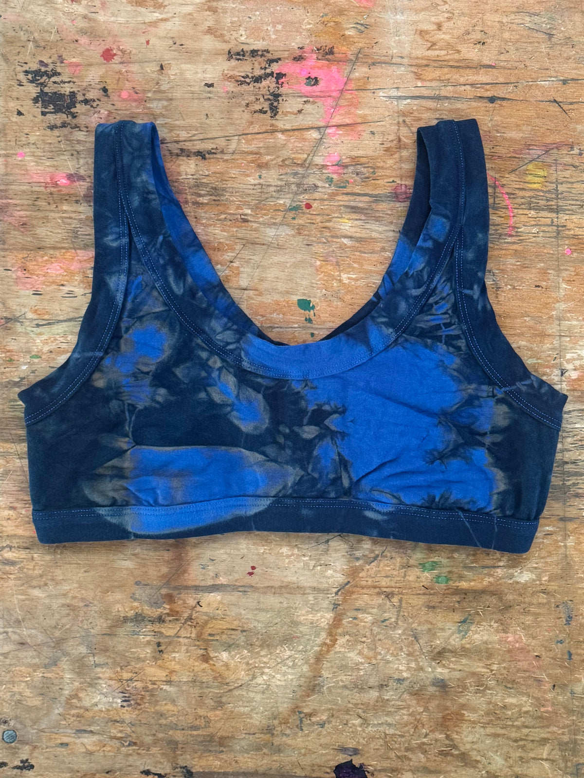 Hand dyed blue Crop top laid on a wooden table  covered in paint