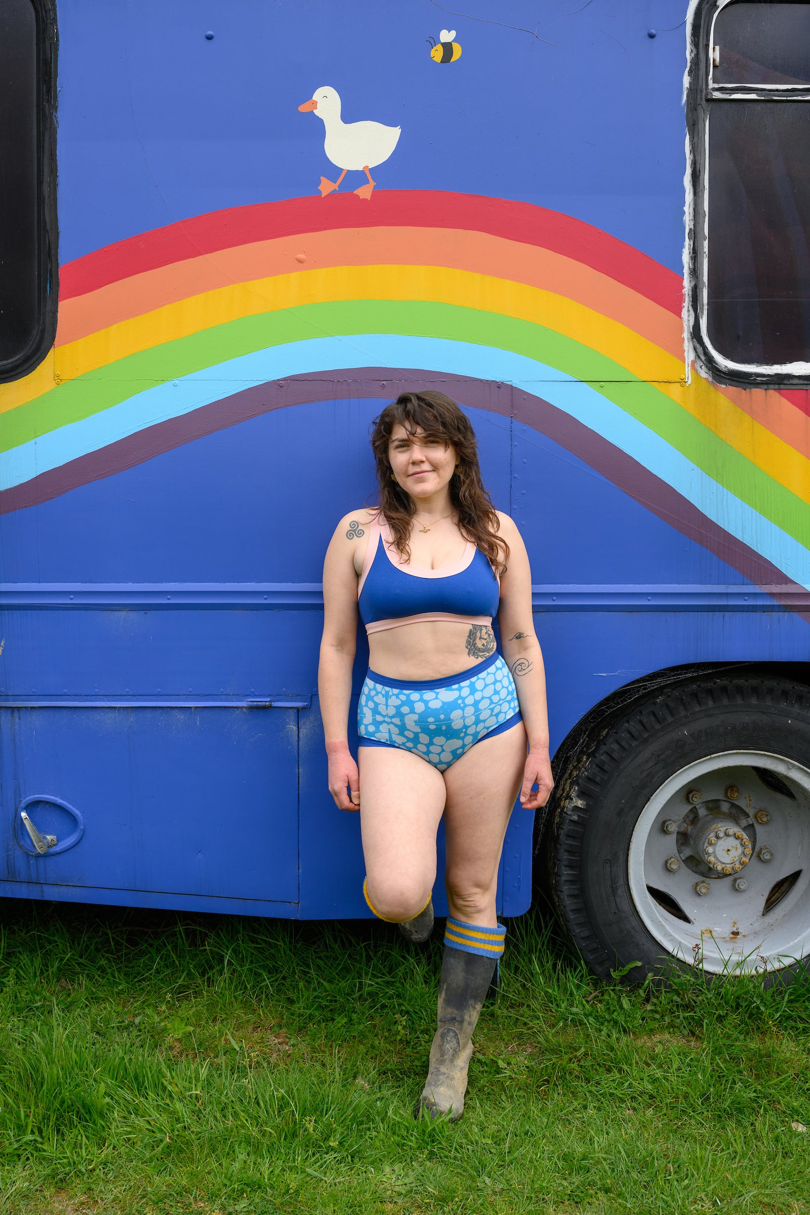 model wearing a blueberry peach crop top and undies leaning on a bus