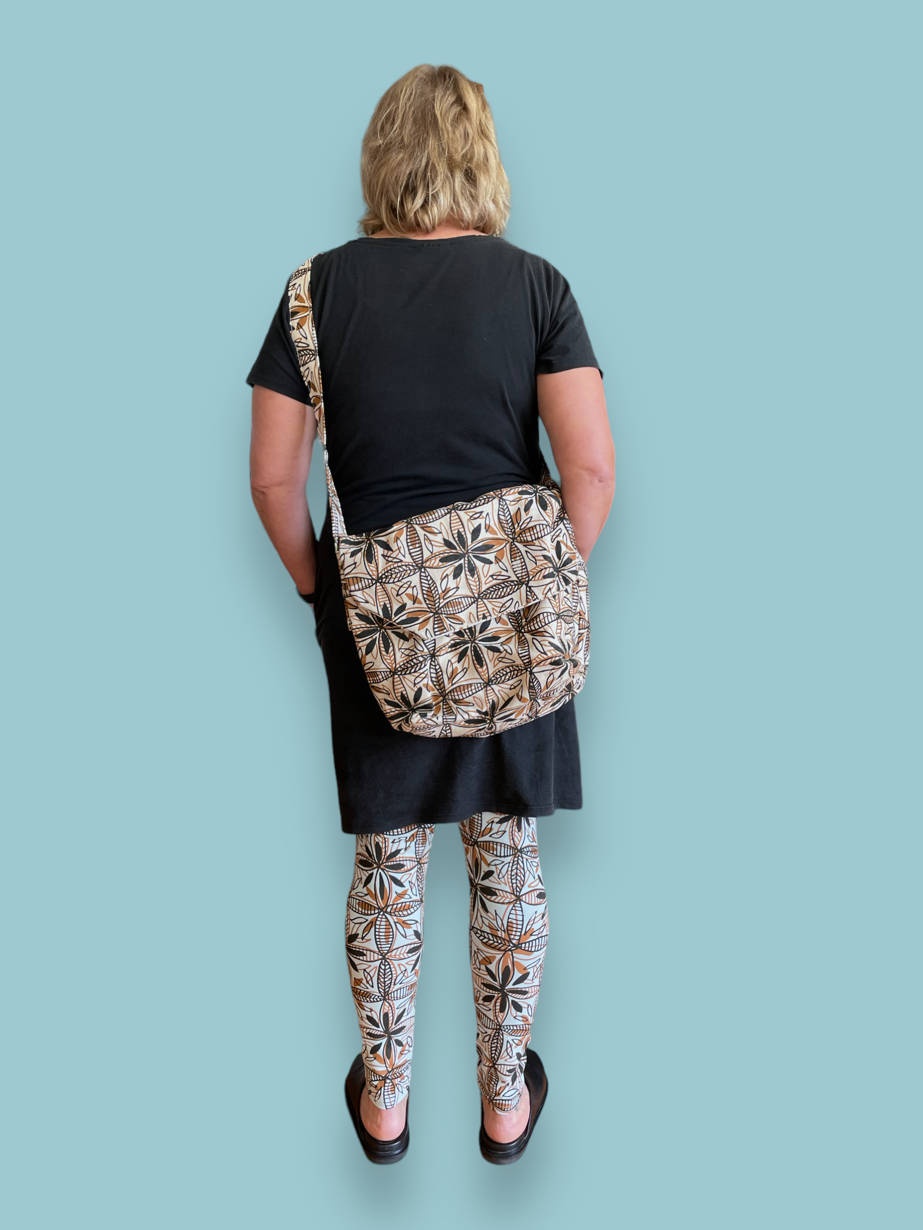 Person wearing satchel with handprinted stylised frangipani flower design