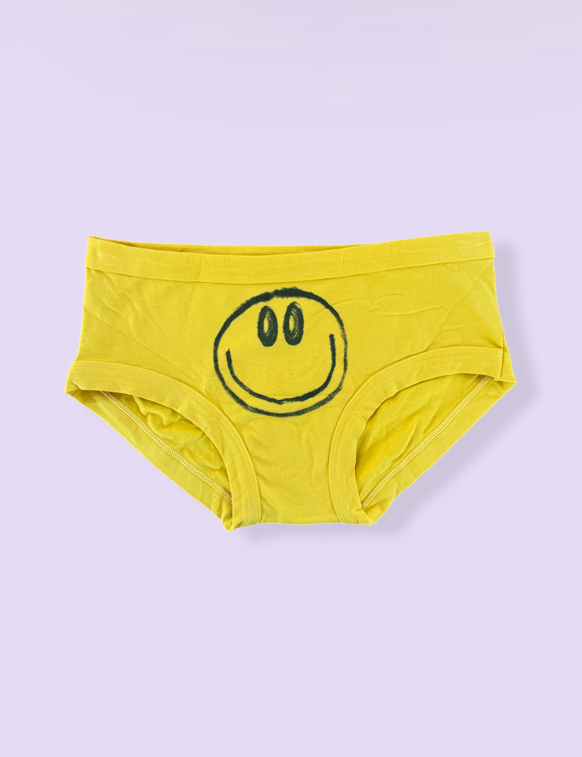 Yellow underwear with a smiley face design on a light purple background