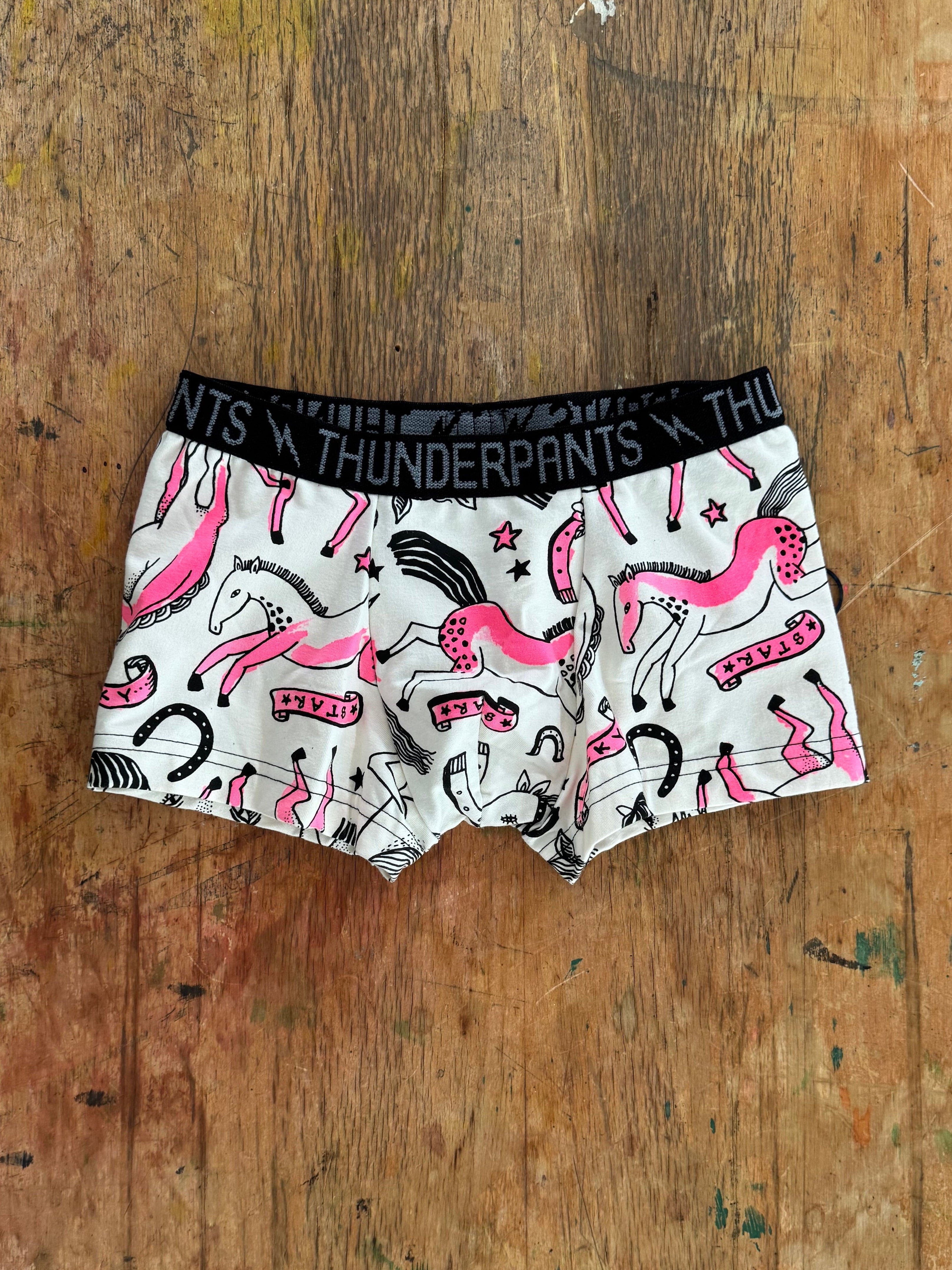 Pair of boxer briefs with pink and black design on a wooden surface